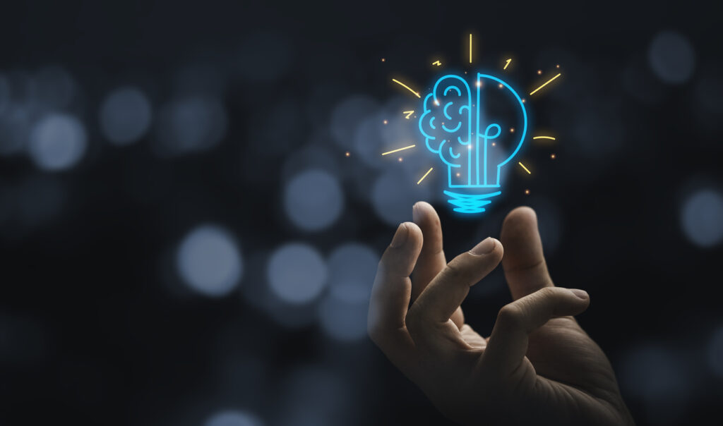 Hand holding a drawing of a virtual lightbulb with brain